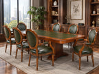 A 9-piece wooden dining room set including a rectangular table with a green leather top and eight matching armchairs with green leather upholstery, shown in a luxury modern office setting.